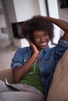 femme afro-américaine à la maison dans une chaise avec tablette et casque photo