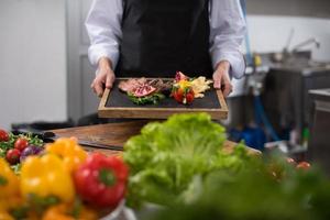 femme chef tenant une assiette de steak de boeuf photo