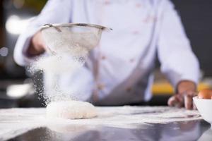 chef saupoudrant de farine sur la pâte à pizza fraîche photo