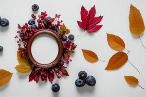 Illustration 3d d'un petit cadre décoratif ovale composé de baies et de feuilles d'automne disposées sur un papier blanc photo