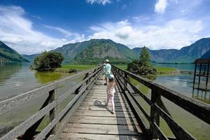 enfants marchant dans un pont en bois sur le lac des alpes autrichiennes à hallstatt, salzkammergut, autriche. photo