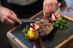 gros plan des mains du chef servant un steak de boeuf photo