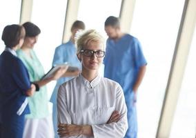 femme médecin avec des lunettes et une coiffure blonde debout devant l'équipe photo