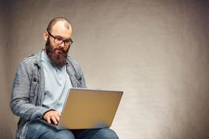 style de vie homme indépendant prospère avec barbe atteint un nouvel objectif avec un ordinateur portable à l'intérieur du loft. photo