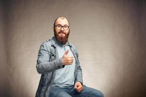 un homme barbu à lunettes montrant le pouce vers le haut, des émotions heureuses photo