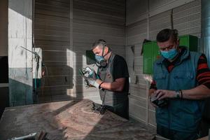travail industriel pendant une pandémie. deux hommes travaillent dans une usine de métaux lourds, portant un masque sur le visage en raison d'une pandémie de coronavirus photo