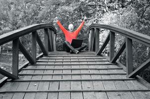 jeune homme d'affaires en chemise rouge travaillant sur un ordinateur portable au pont photo