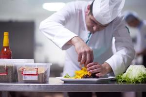 chef dans la cuisine de l'hôtel préparant et décorant la nourriture photo