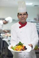 chef dans la cuisine de l'hôtel préparant et décorant la nourriture photo