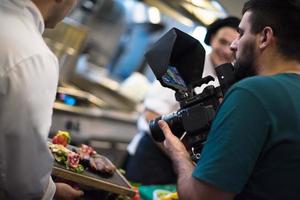 vidéaste enregistrant pendant que les cuisiniers de l'équipe et les chefs préparent le repas photo