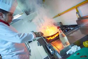 le chef de la cuisine de l'hôtel prépare la nourriture avec le feu photo