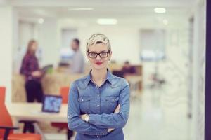 portrait de jeune femme d'affaires au bureau avec l'équipe en arrière-plan photo