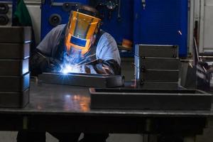 un soudeur professionnel effectue des travaux avec des pièces métalliques en usine, des étincelles et de l'électricité. bannière de travailleur de l'industrie. photo