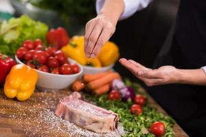 chef mettant du sel sur une tranche juteuse de steak cru photo