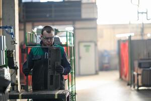 un ouvrier en uniforme travaillant dans une usine moderne de production et de transformation de métaux assemble des pièces d'une nouvelle machine sur son bureau photo