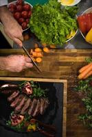 vue de dessus des mains du chef servant un steak de boeuf photo