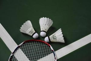 Volant et raquette de badminton blanc crème sur sol rouge dans un terrain de badminton intérieur, espace de copie, mise au point douce et sélective sur les volants. photo