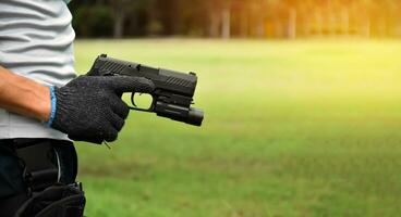 pistolet tenant dans les mains d'un tireur au club de tir, mise au point douce et sélective sur le pistolet, concept de tir sportif, garde du corps, formation à la sécurité, mafias, gangsters et autoprotections. photo