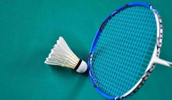 volant de badminton blanc crème et raquette au sol dans un terrain de badminton intérieur, espace de copie, mise au point douce et sélective sur les volants. photo