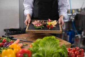 femme chef tenant une assiette de steak de boeuf photo