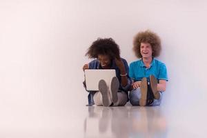 couple multiethnique assis sur le sol avec un ordinateur portable et une tablette photo