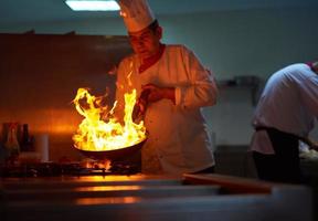 le chef de la cuisine de l'hôtel prépare la nourriture avec le feu photo