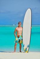 homme avec planche de surf sur la plage photo