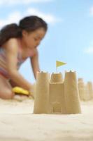 château de sable avec fille jouant sur la plage