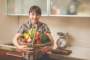 garçon prépare des légumes dans la cuisine - végétariens en bonne santé photo