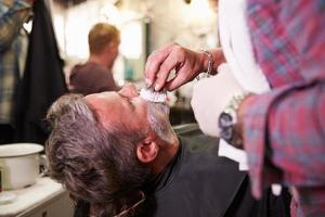 Barbier mâle prépare le client pour le rasage en boutique