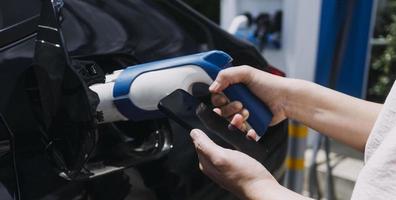 brancher à la main un chargeur dans une prise de voiture électrique.voiture électrique ou ev se recharge à la station photo