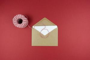 une enveloppe avec une lettre allongée sur un fond rouge en guise de salutations pour les vacances photo