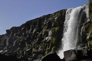une grande cascade sur une falaise rocheuse - oxarafoss dans le parc national de thingvellir. photo