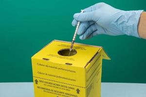 boîte de collecte des déchets hospitaliers contaminés avec la main plaçant une seringue photo