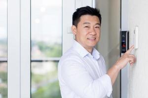 portrait d'homme d'affaires asiatique, l'homme entre dans un bureau moderne, utilise une sonnette avec empreinte digitale photo