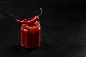 bocal en verre avec des pâtes de tomates épicées classiques faites maison ou une sauce à pizza avec des épices et des herbes photo