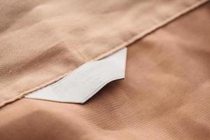 étiquette de vêtement blanc vierge sur fond de texture de tissu marron photo