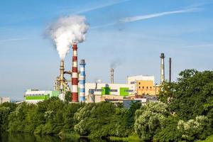 tuyaux de la scierie de l'usine de menuiserie avec une belle réflexion dans l'eau bleue de la rivière. notion de pollution atmosphérique. paysage industriel pollution environnementale déchets de centrale thermique photo