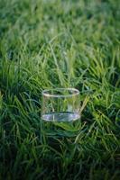 verre d'eau dans l'herbe verte avec fond sur le dessus photo
