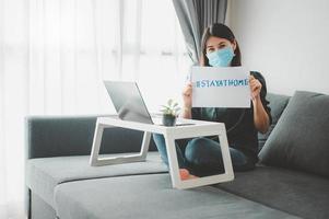 femme portant un masque facial travaillant à la maison photo