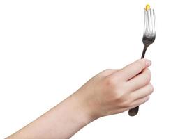 main tenant une fourchette avec des graines de maïs jaune empalées photo