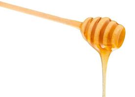 miel clair coulant d'une cuillère en bois isolée photo
