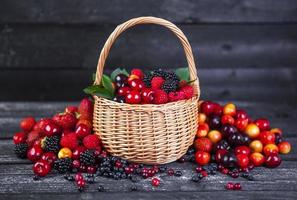 baies mélangées dans le panier sur fond de bois foncé photo