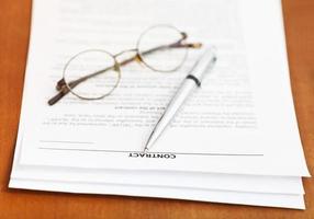 Contrat et stylo argenté et lunettes sur table photo