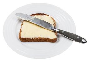 Pain et beurre avec couteau de table sur plaque blanche photo