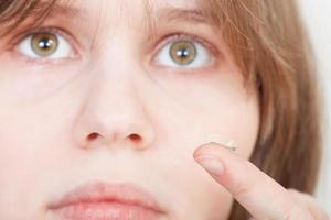 fille tient une lentille de contact sur votre doigt photo