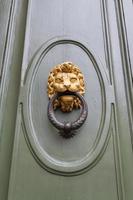 Heurtoir à tête de lion sur la porte verte à Florence photo