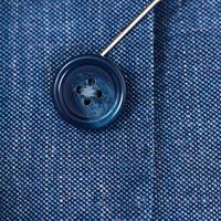 fixation d'un bouton sur un tissu de soie bleu à l'aide d'une aiguille photo