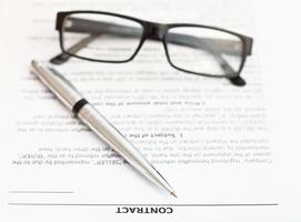 Stylo et lunettes en argent sur contrat de vente photo