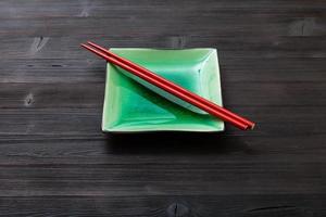 soucoupe verte avec des baguettes sur une planche marron foncé photo